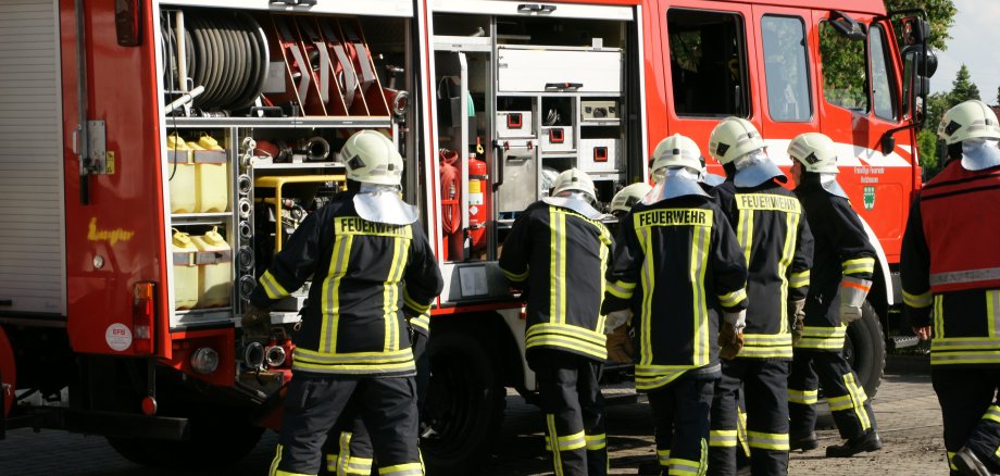 Feuerwehrleute sind im Einsatz zu sehen mit Feuerwehrfahrzeug